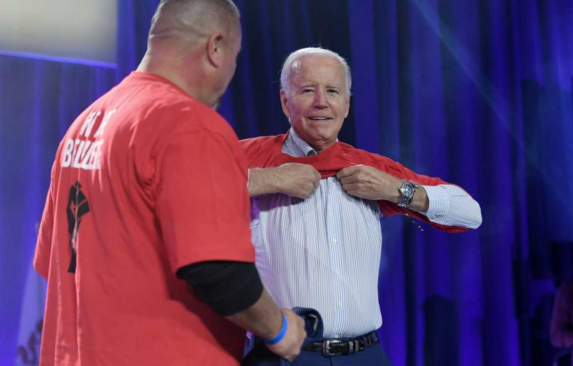 US President Joe Biden puts on a local United Auto Workers shirt US President Joe Biden puts on a local United Auto Workers shirt