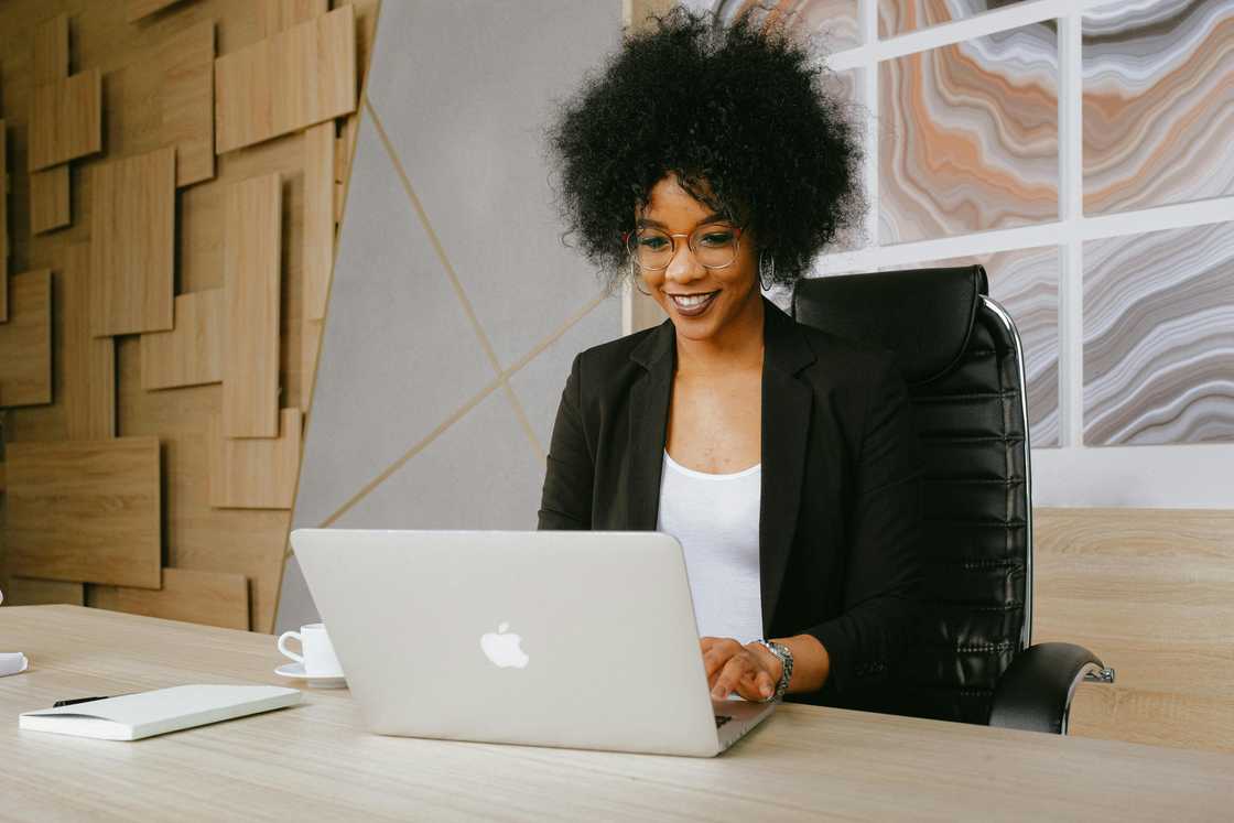 A woman wearing a black blazer using MacBook