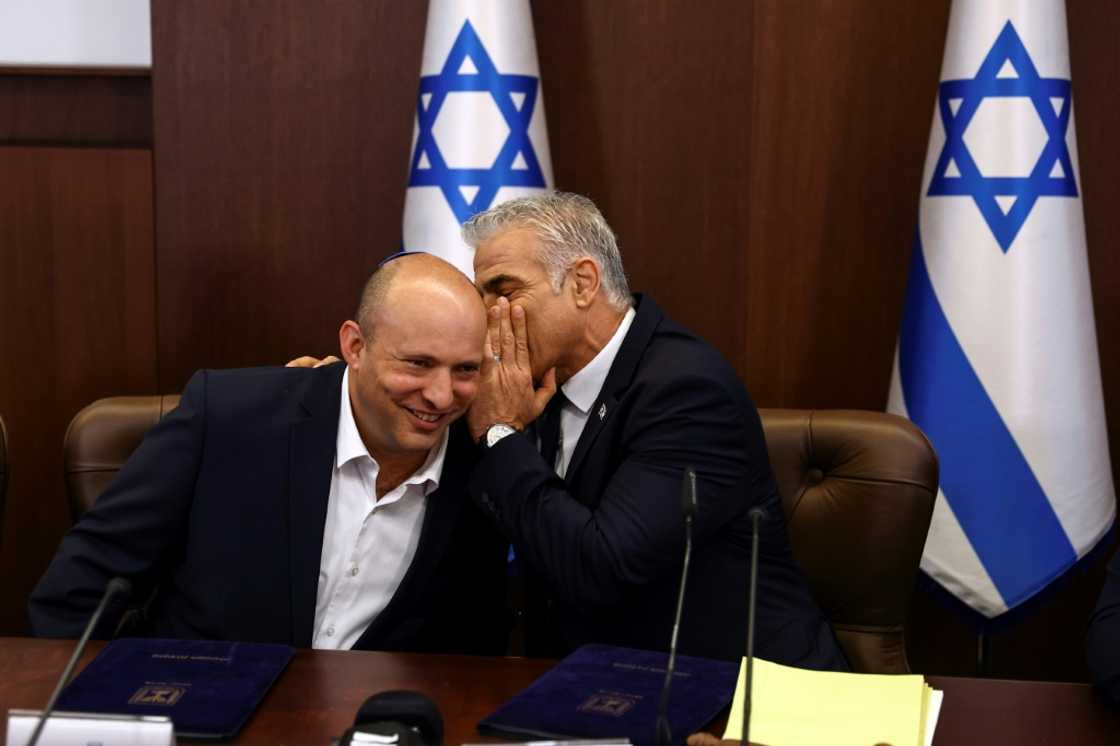Israeli Prime Minister Yair Lapid whispers to his predecessor Naftali Bennett at the weekly cabinet meeting in Jerusalem on Sunday