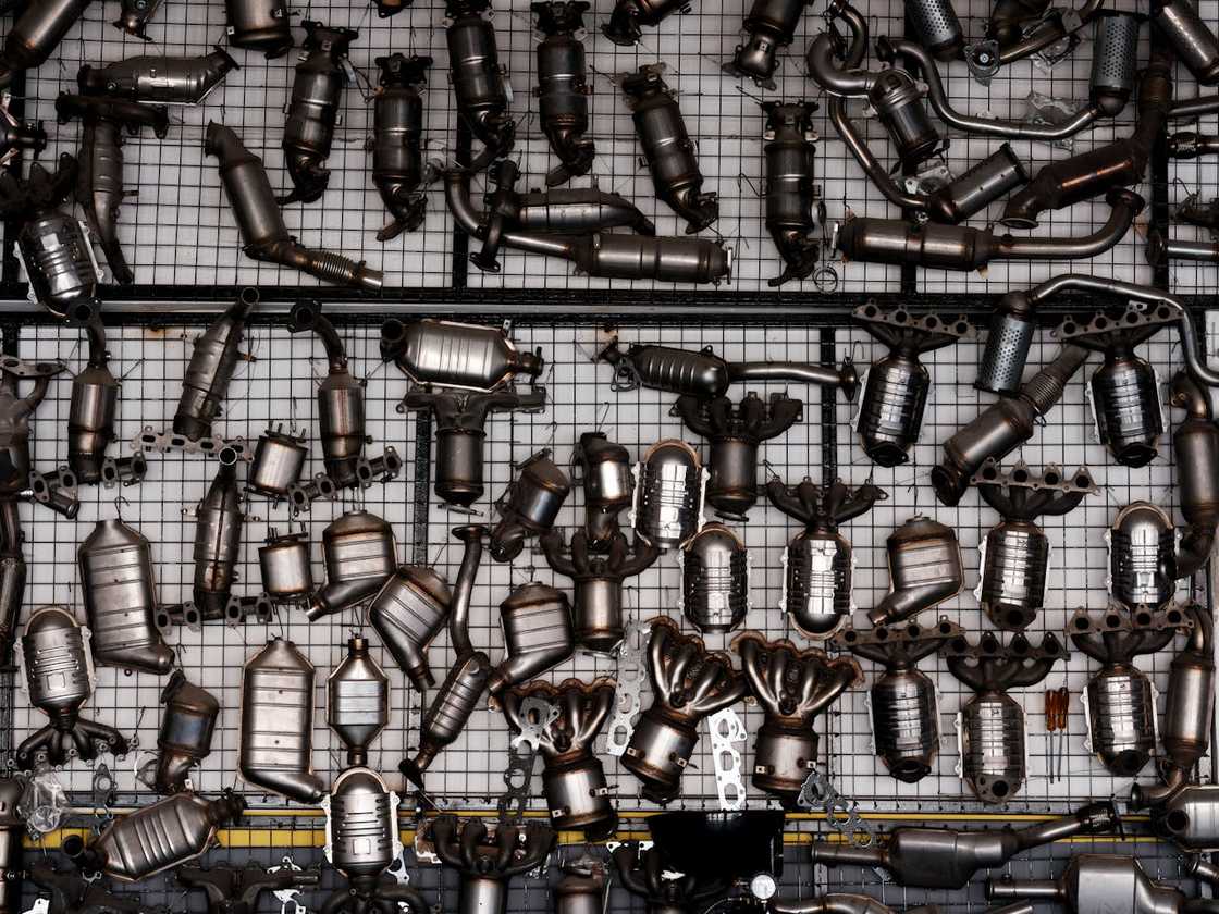 Assorted car exhaust and catalytic converter parts arranged on a wall. Assorted car exhaust and catalytic converter parts arranged on a wall.
