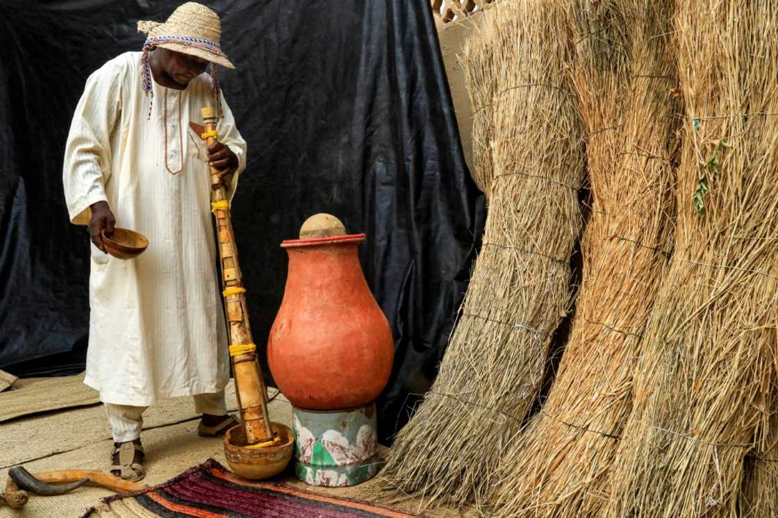 Dafallah al-Haj Ali Mustafa pours water down the pipe of the traditional "wazza" instrument to wet and soften it before playing