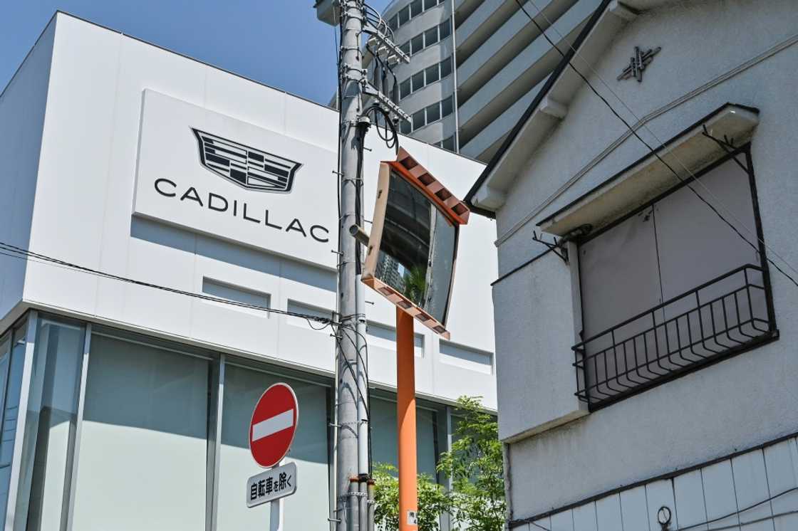 A sign for Cadillac cars is displayed on the outside wall of a car dealership which sells US auto brands Cadillac and Chevrolet in Tokyo