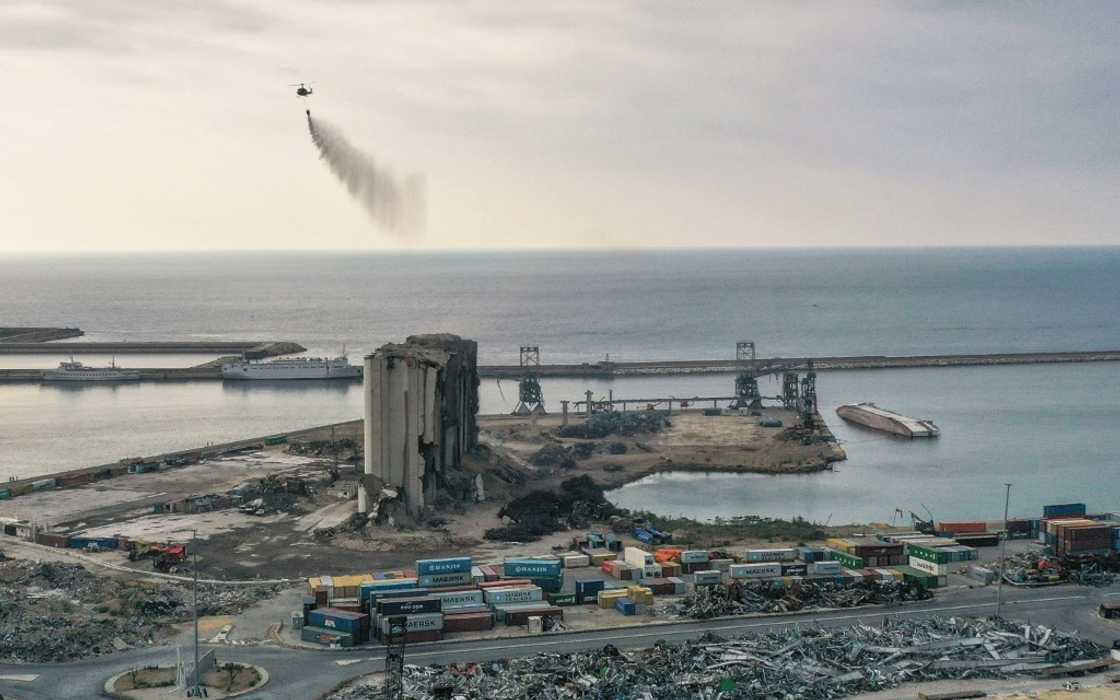 A Lebanese army helicopter releases water over the heavily damaged grain silos at the port of the capital Beirut A Lebanese army helicopter releases water over the heavily damaged grain silos at the port of the capital Beirut