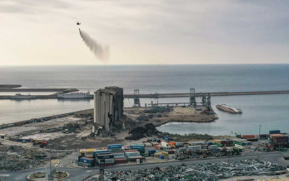 A Lebanese army helicopter releases water over the heavily damaged grain silos at the port of the capital Beirut