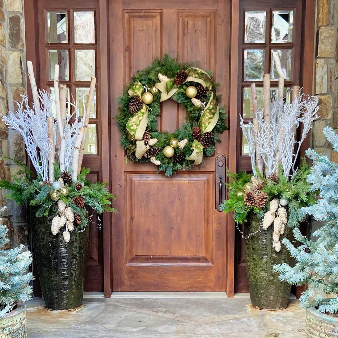 A beautiful potted evergreen arrangement with a wreath at the door