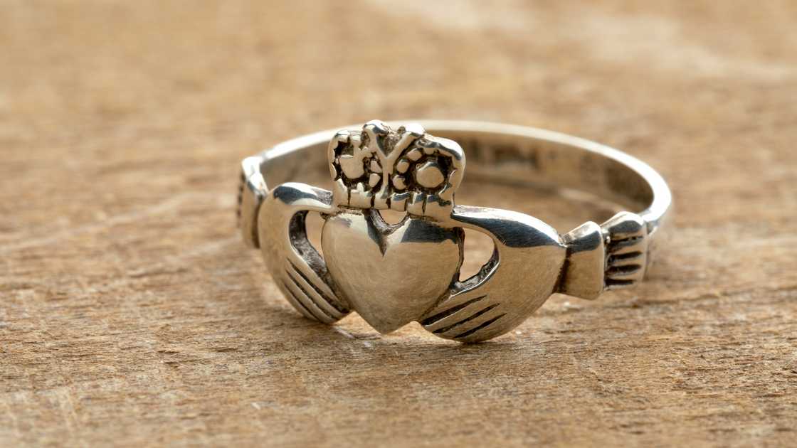 Silver Irish Claddagh ring on a wooden background