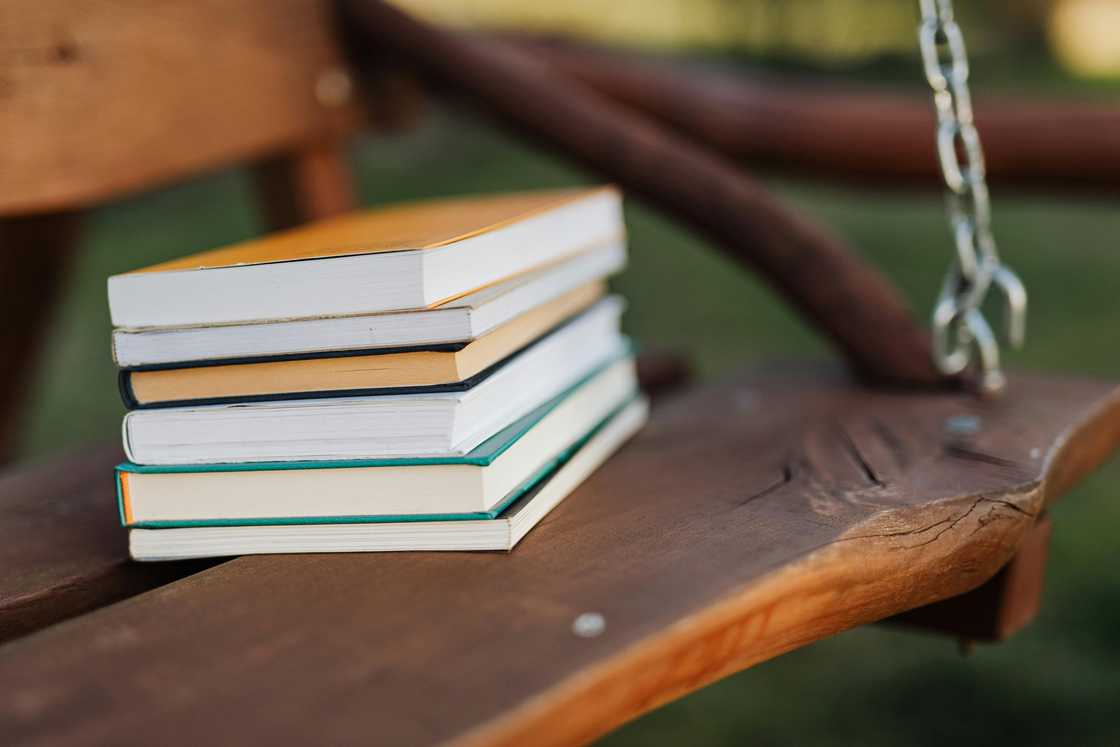 A stack of books on a wooden swing A stack of books on a wooden swing