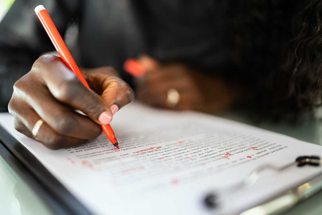 A teacher correcting a report card with a pen.