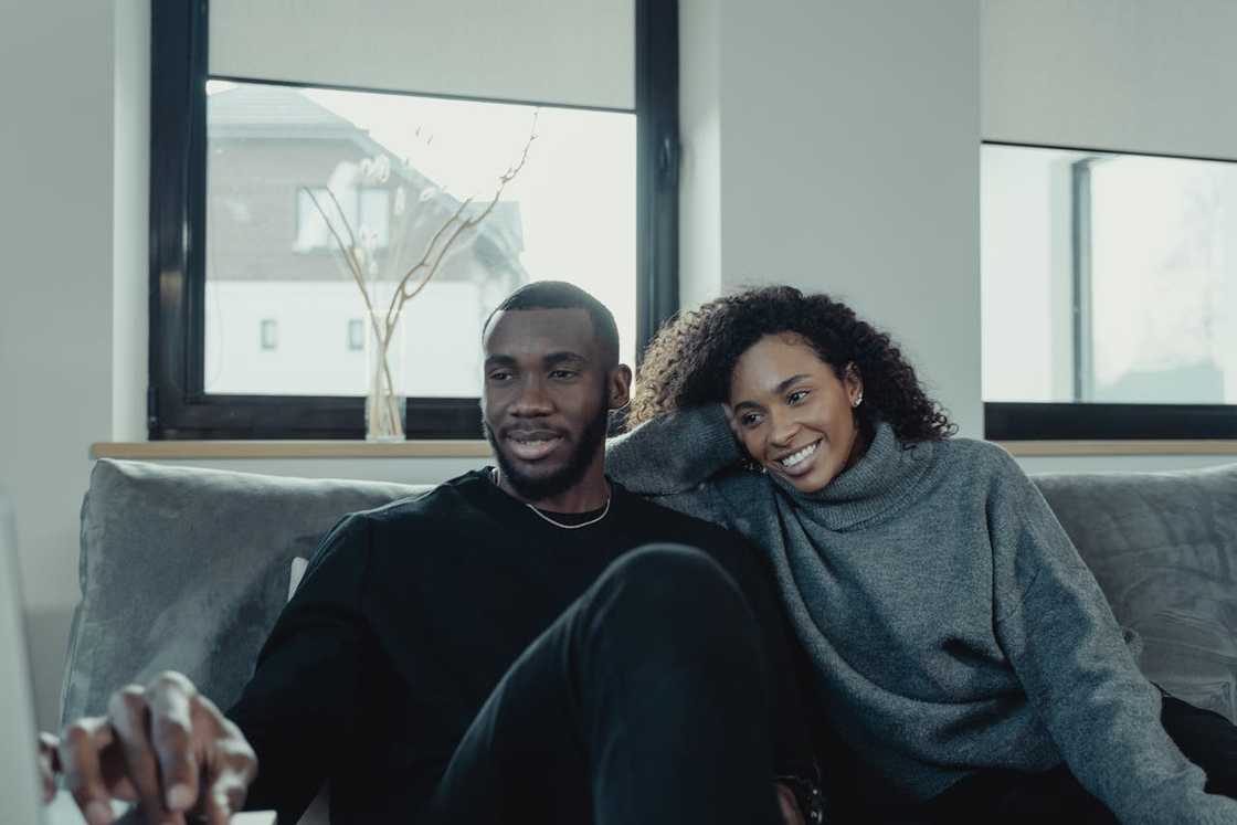 A couple sits close together on a sofa, smiling and relaxed at home. A couple sits close together on a sofa, smiling and relaxed at home.