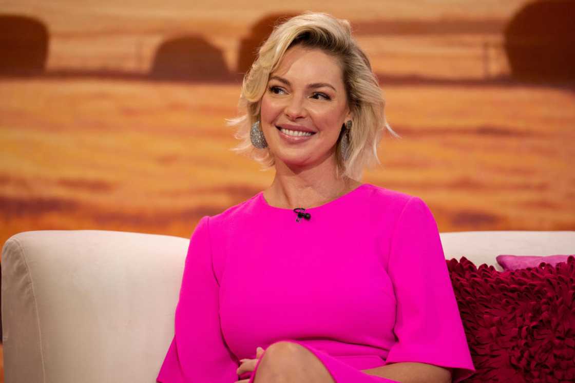 Katherine Heigl sitting on a couch wearing a pink dress on an interview Katherine Heigl sitting on a couch wearing a pink dress on an interview