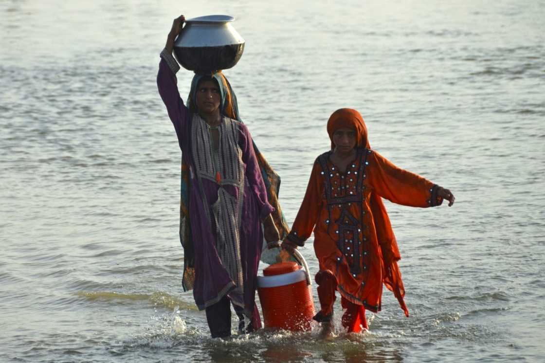 Girls wade through floodwater while carrying drinking water in Jaffarabad, Balochistan Girls wade through floodwater while carrying drinking water in Jaffarabad, Balochistan