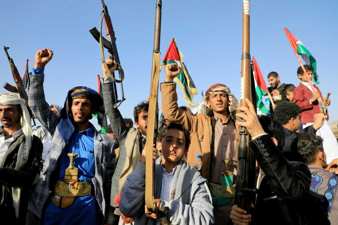 Huthi fighters brandish weapons during a protest in Sanaa on January 12, 2024 following US and British forces strikes targeting the Yemeni rebel group