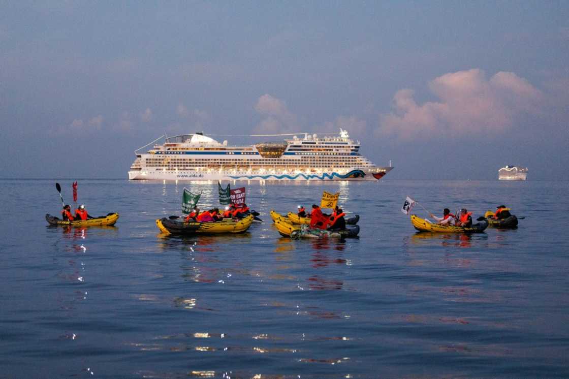 Activists from the NGO "Stop croisieres" and "Extinction Rebellion France" hold banners while they block a cruise ship