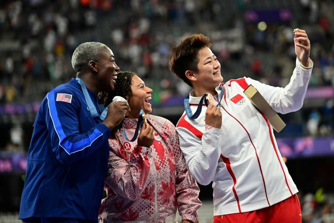 Winners of the women's hammer throw take a selfie with a Samsung flip phone