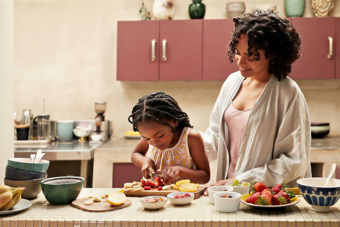 A smiling woman standing by her daughter A smiling woman standing by her daughter