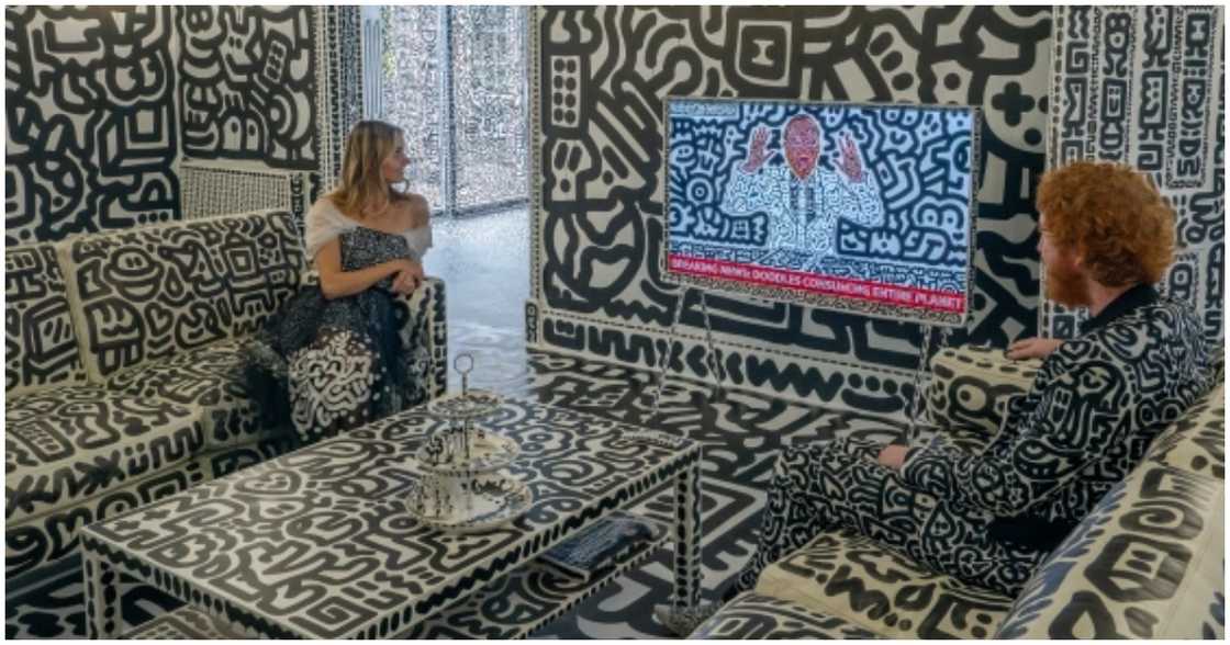 Sam and his partner sit in the living room covered with doodle art Sam and his partner sit in the living room covered with doodle art