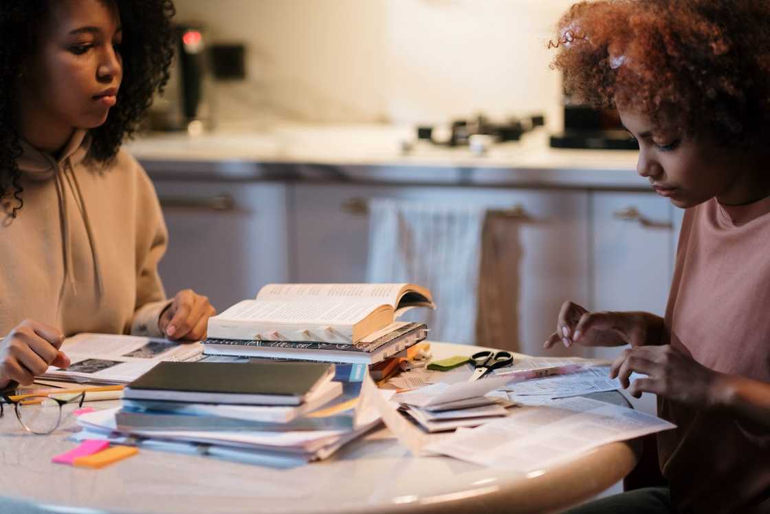 Two women sit at a table sorting through documents. Two women sit at a table sorting through documents.