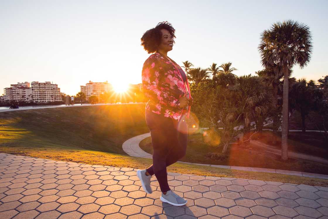 Woman walking alone through a quiet city park at dusk. Woman walking alone through a quiet city park at dusk.