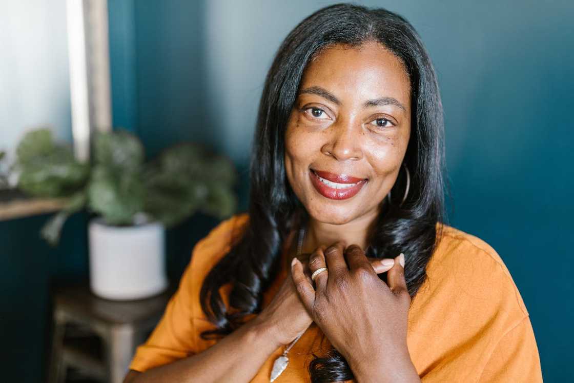 A woman smiles gently while holding her hands to her chest. A woman smiles gently while holding her hands to her chest.
