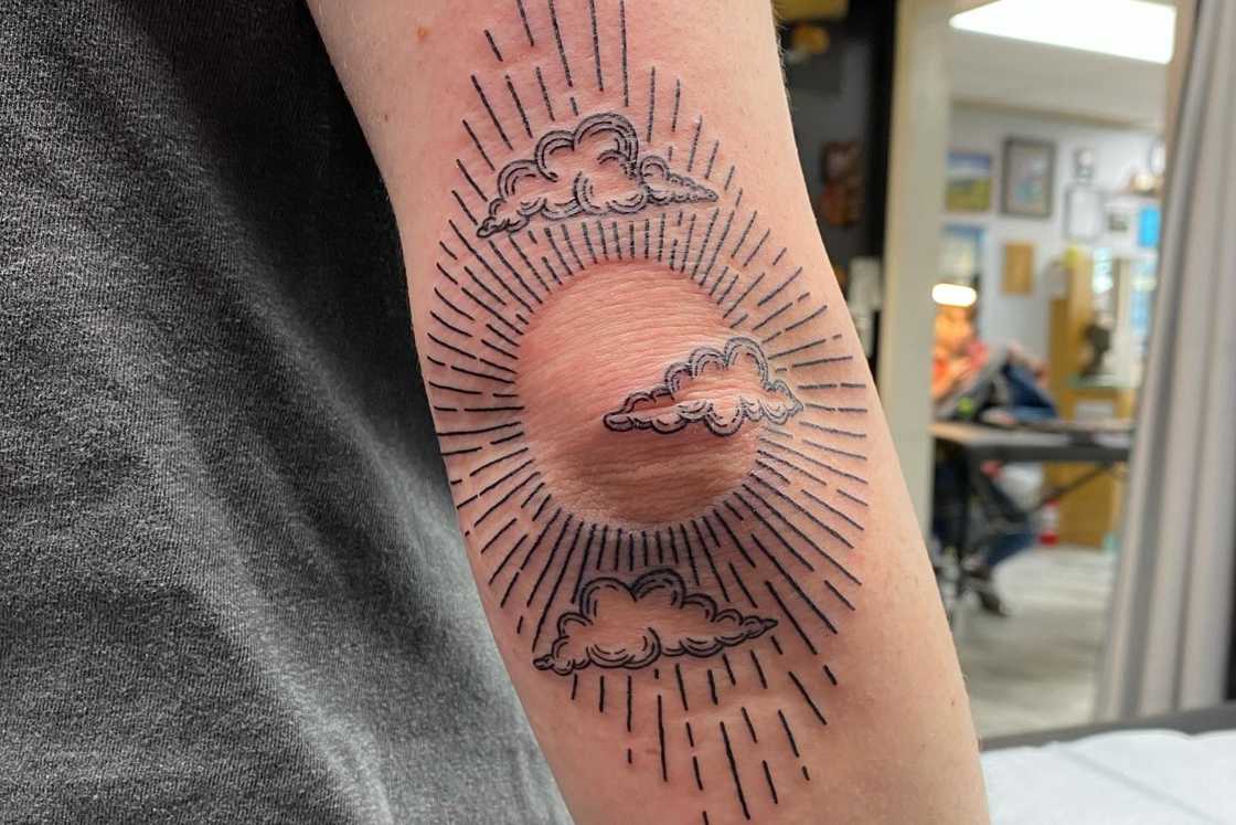 A sun elbow tattoo featuring some clouds A sun elbow tattoo featuring some clouds