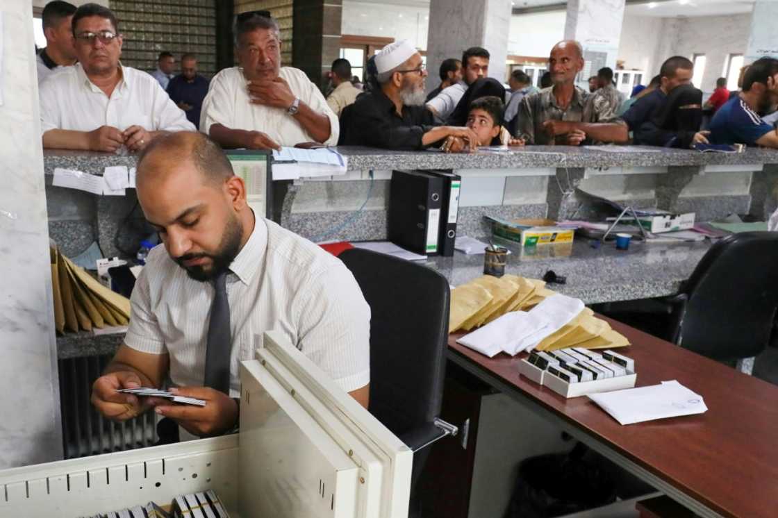 A bank teller in Misrata looks for a customer's debit card -- despite a shift towards cashless transactions many vendors do not accept card payments A bank teller in Misrata looks for a customer's debit card -- despite a shift towards cashless transactions many vendors do not accept card payments