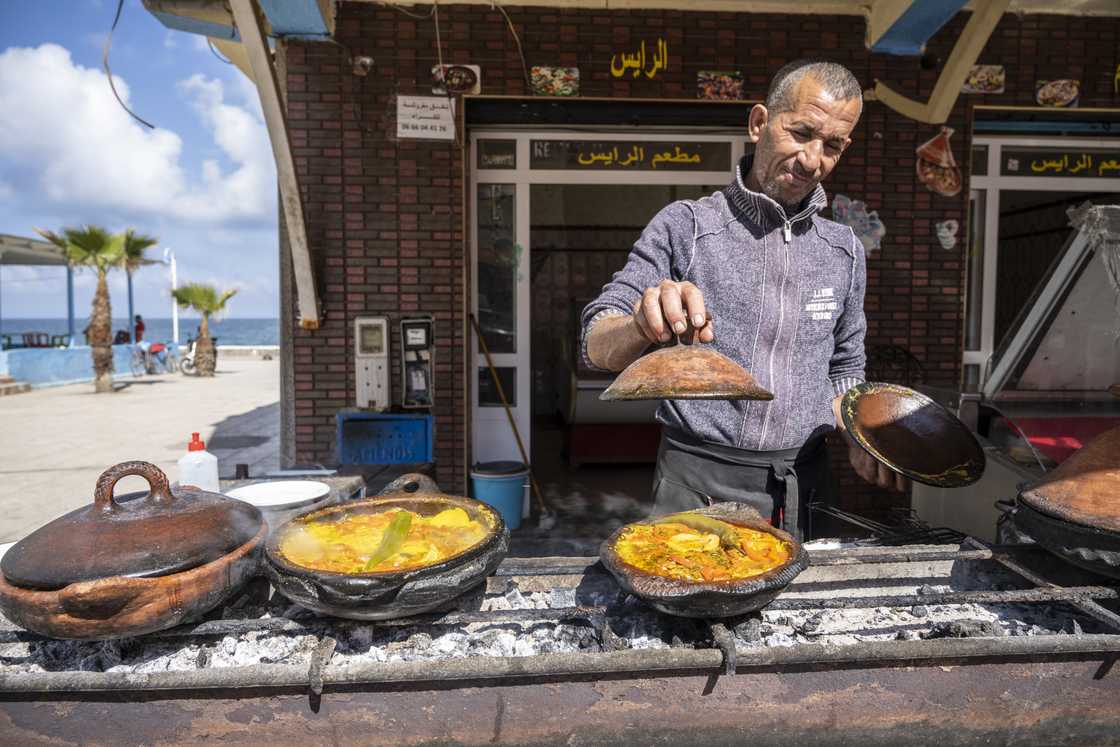 A man cooking the traditional tajine for lunch in a street restaurant A man cooking the traditional tajine for lunch in a street restaurant