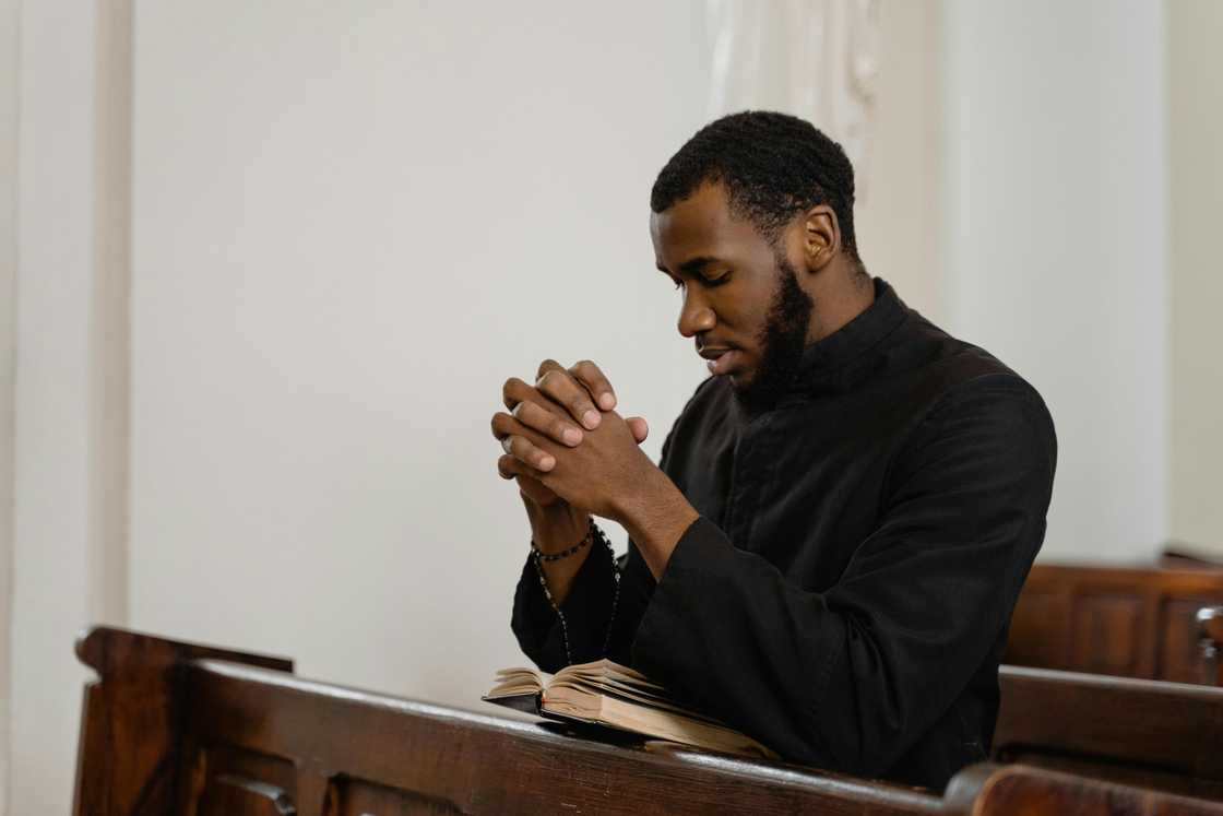 A religious man in black shirt praying solemnly A religious man in black shirt praying solemnly