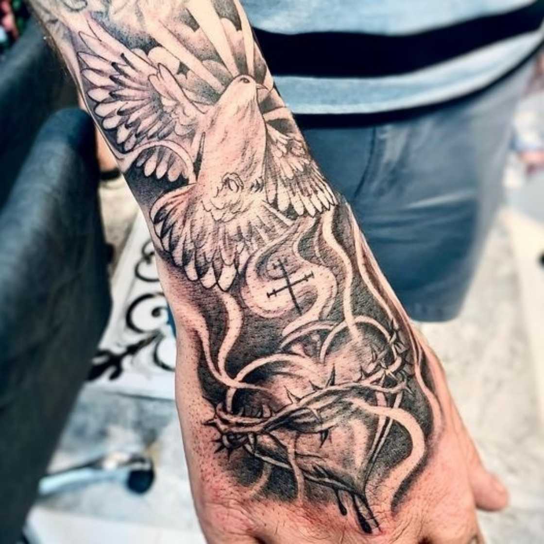 Sacred heart and dove on hand tattoo