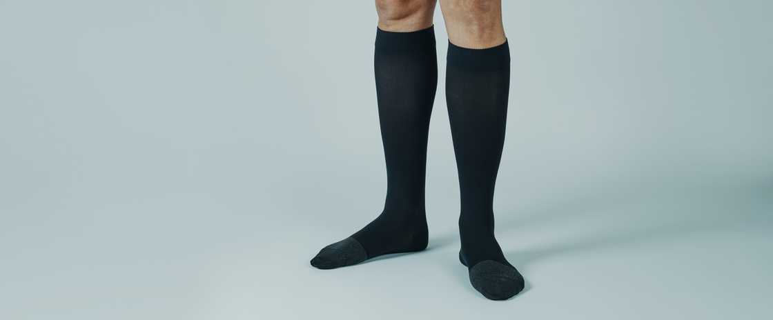 A person with black compression socks and flat shoes A person with black compression socks and flat shoes