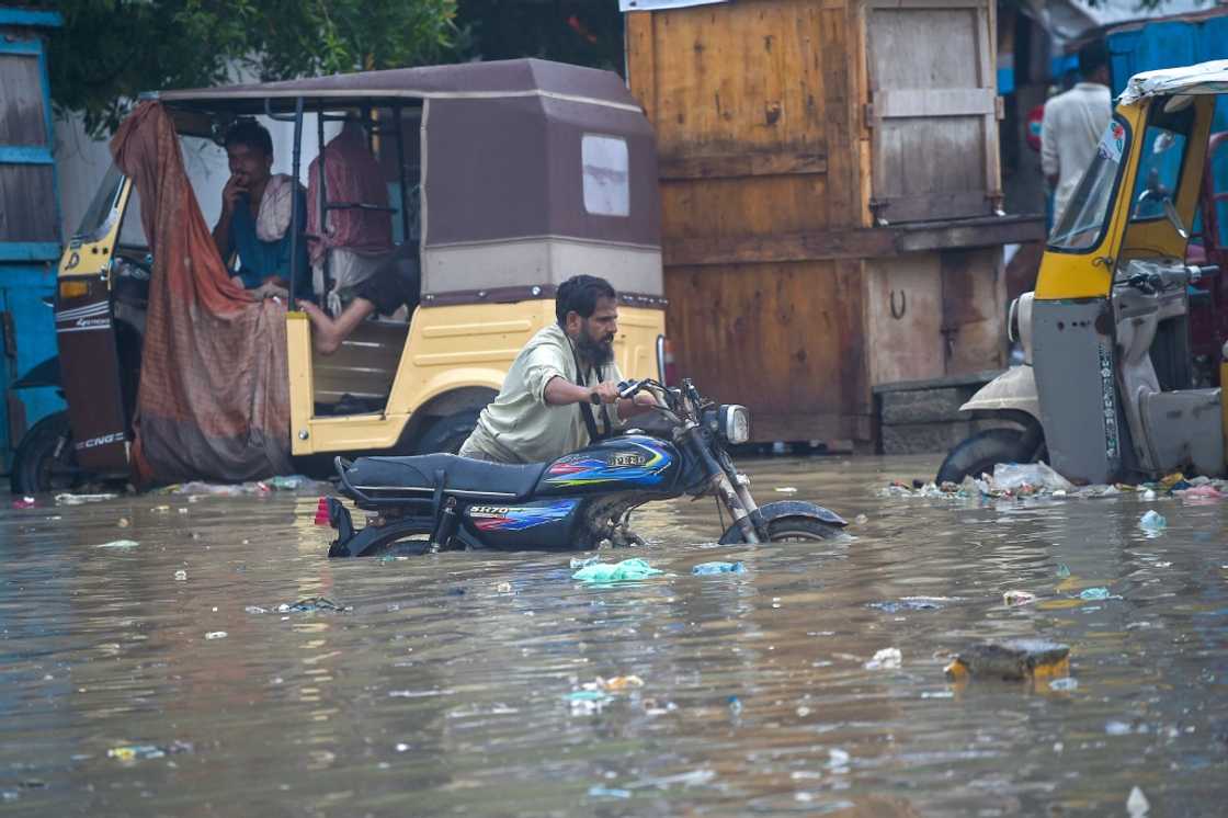 A man pushes his motorbike through a flooded street after heavy monsoon rain in Karachi A man pushes his motorbike through a flooded street after heavy monsoon rain in Karachi