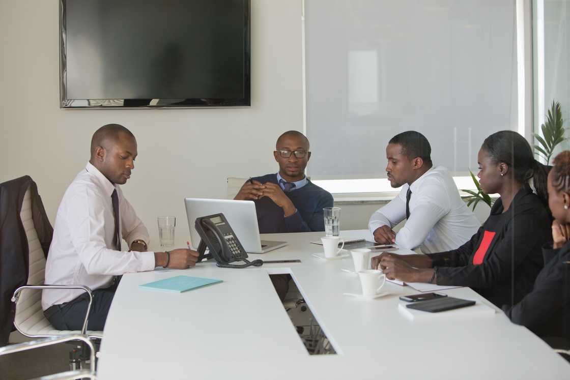 Managers listen to a call playback in a call centre office meeting.