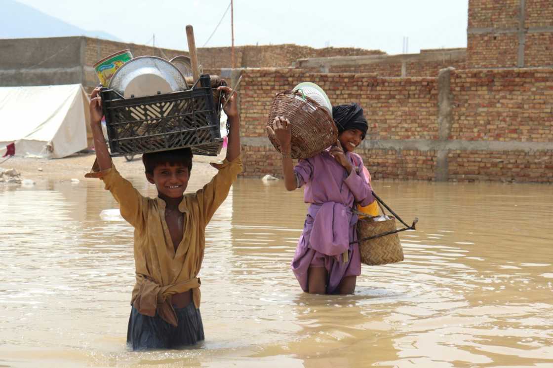 Children carrying household items through a flooded area near Quetta in Pakistan during the monsoon rains Children carrying household items through a flooded area near Quetta in Pakistan during the monsoon rains