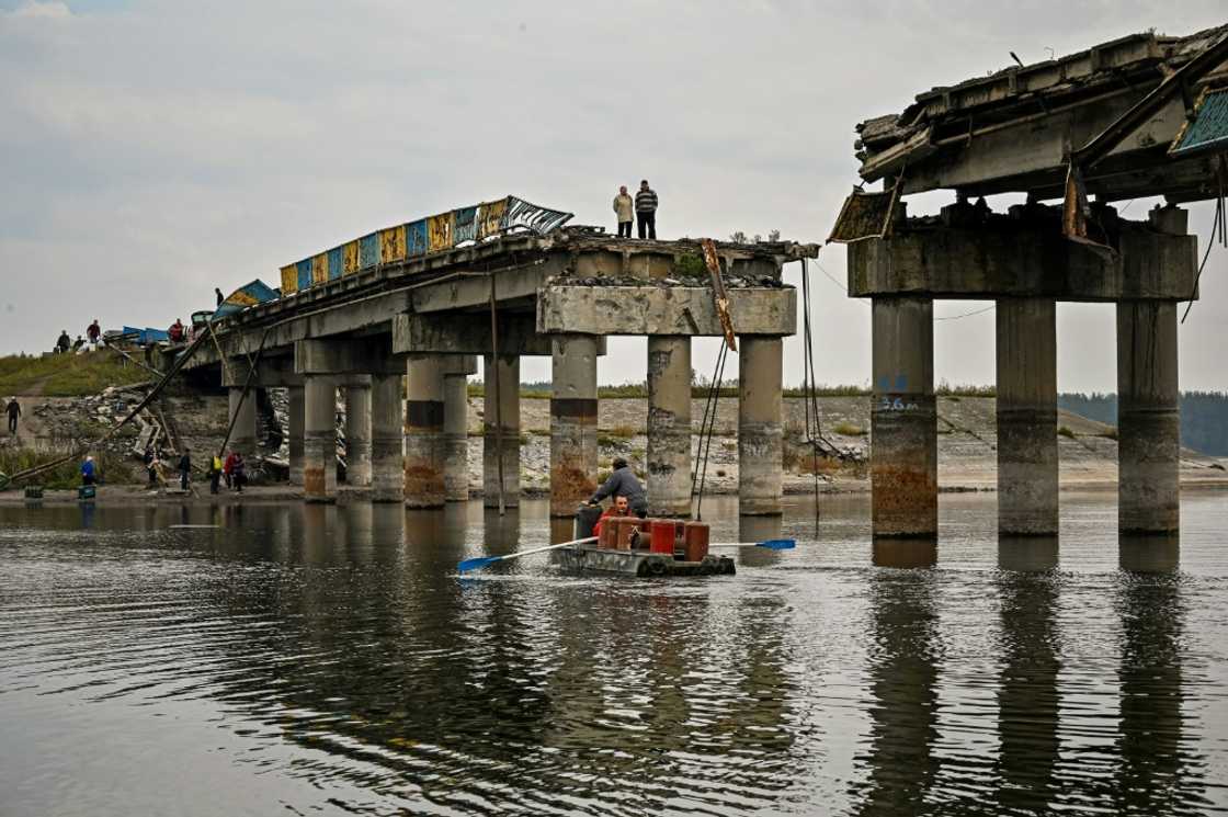 Local residents cross the Donets river next to a destroyed bridge Local residents cross the Donets river next to a destroyed bridge