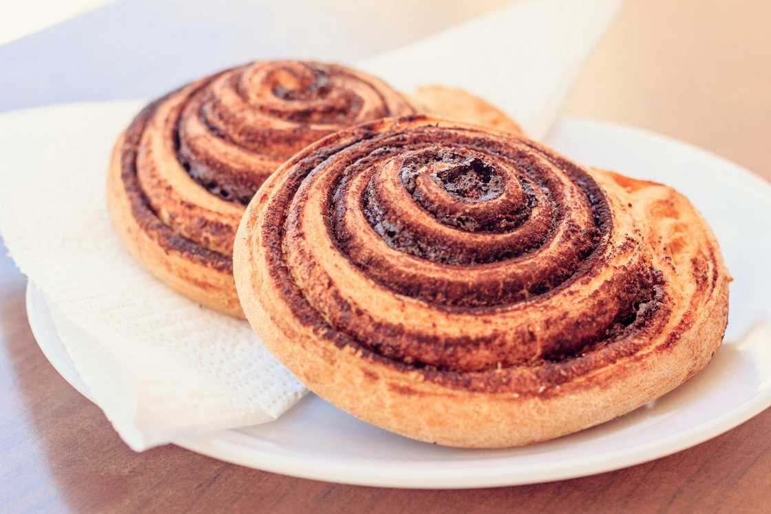 A close-up of two cinnamon rolls on a white plate