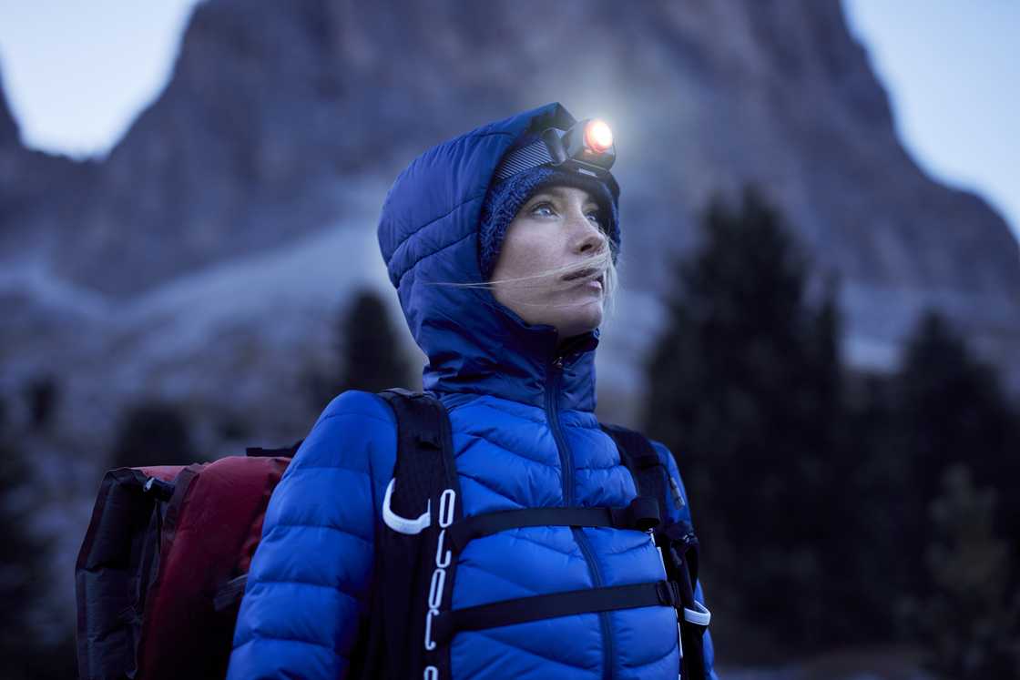 A young woman wearing a headlamp at dusk in the mountains A young woman wearing a headlamp at dusk in the mountains