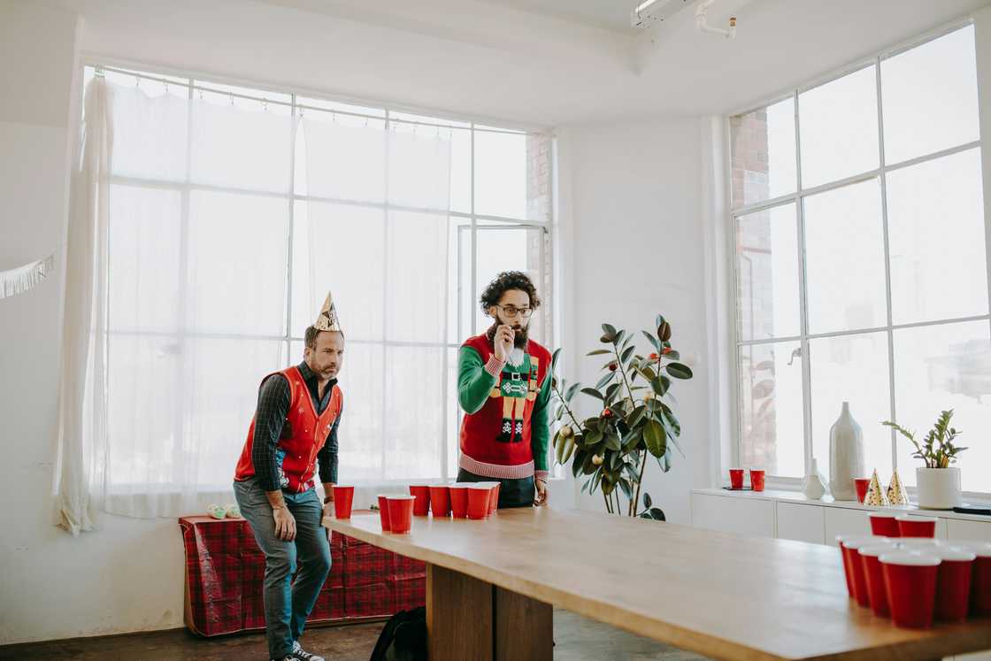 Men playing beer pong game in the office Men playing beer pong game in the office