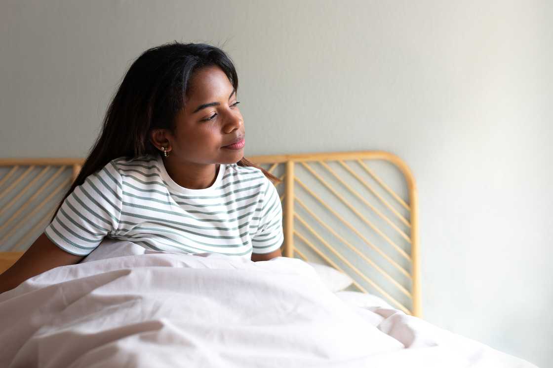Young woman sitting on bed after waking up Young woman sitting on bed after waking up
