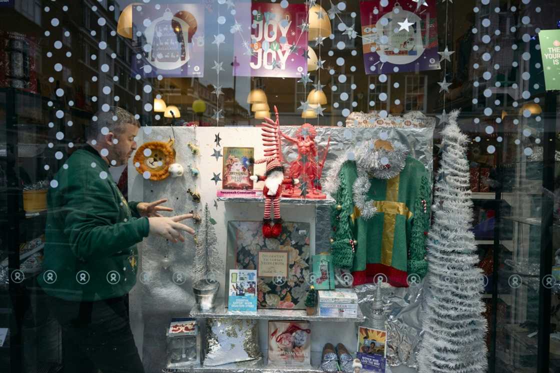 An employee rearranges the Christmas display in the front window of an Oxfam charity shop in London, amid a surge of interest in buying 'pre-loved' goods for gifts