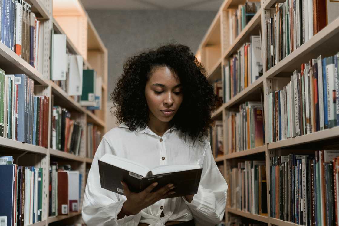 A young woman is reading a book inside a library