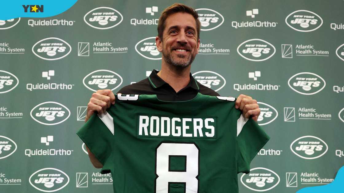 American football quarterback Aaron Rodgers poses with a jersey. American football quarterback Aaron Rodgers poses with a jersey.