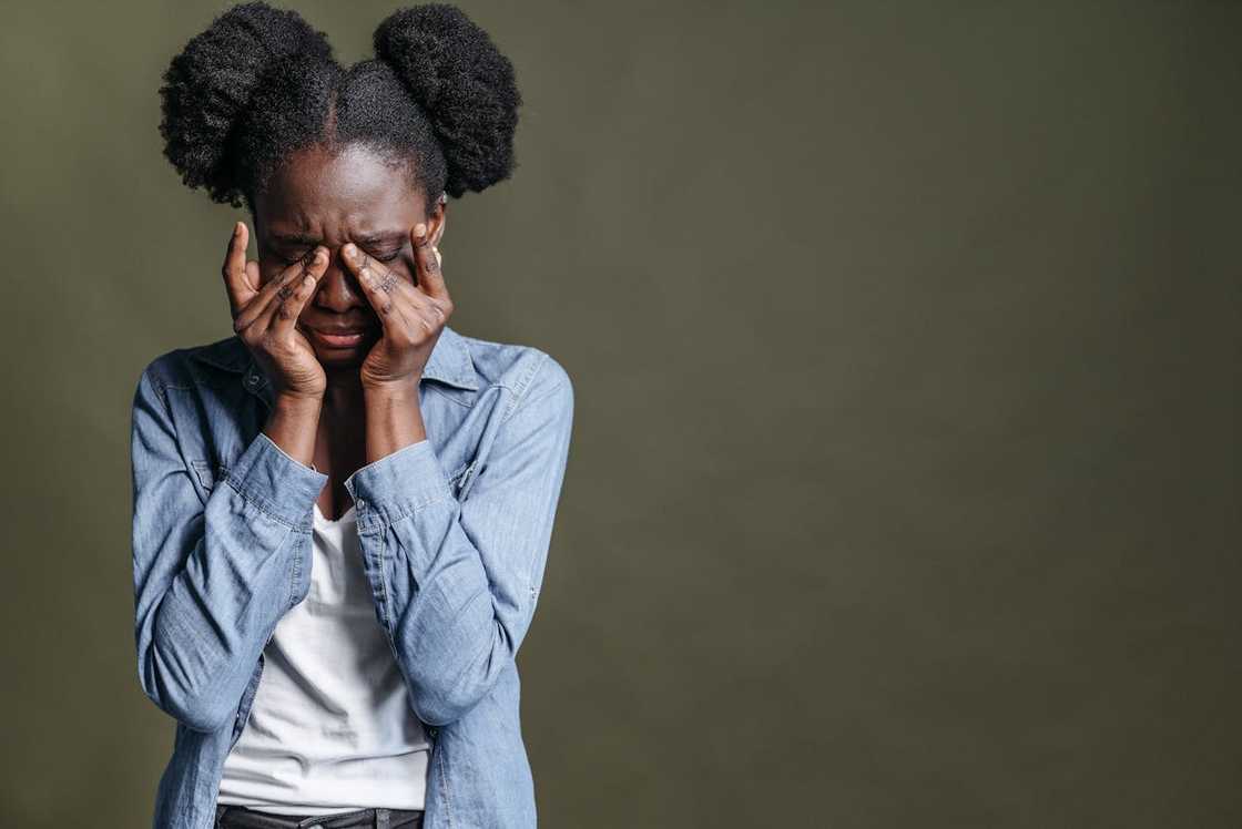 A teenager covers her face with her hands in visible distress. A teenager covers her face with her hands in visible distress.