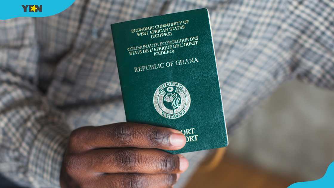 A hand holding a passport from Ghana A hand holding a passport from Ghana