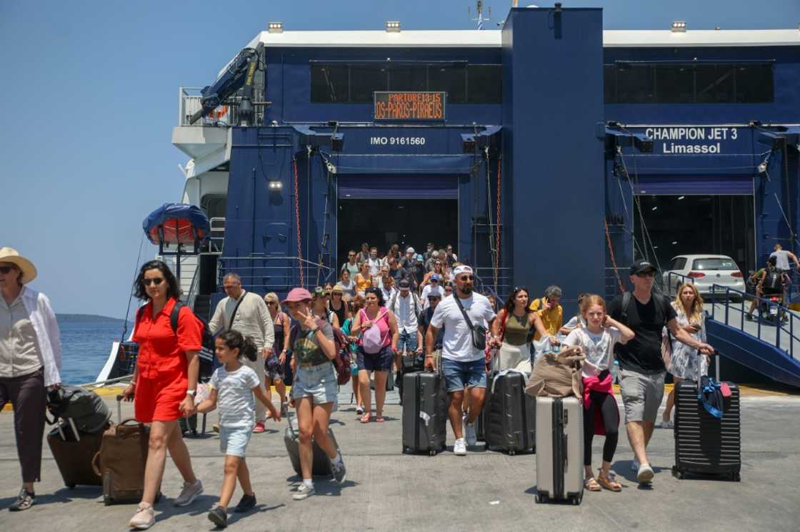 Tourists disembark from a boat in the harbor