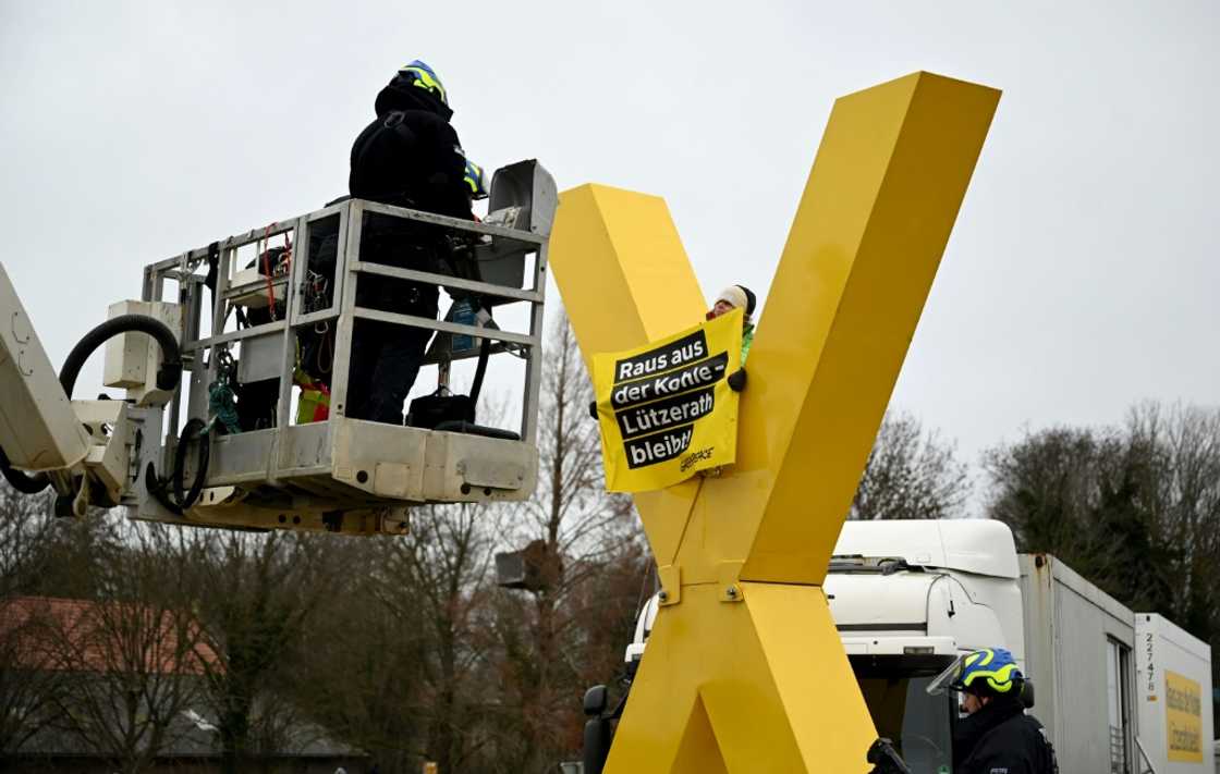 Policemen on a lifting platform prepare to remove an anti-coal activist sitting on a giant yellow X sculpture on January 10, 2023 in Luetzerath, western Germany Policemen on a lifting platform prepare to remove an anti-coal activist sitting on a giant yellow X sculpture on January 10, 2023 in Luetzerath, western Germany