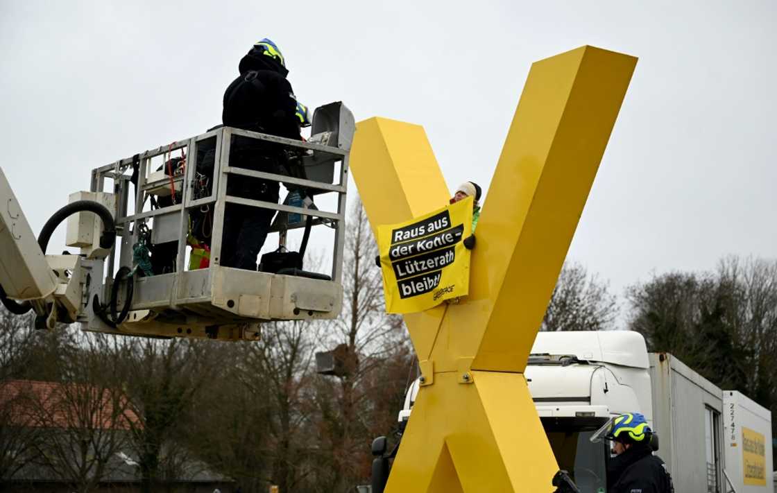 Policemen on a lifting platform prepare to remove an anti-coal activist sitting on a giant yellow X sculpture on January 10, 2023 in Luetzerath, western Germany