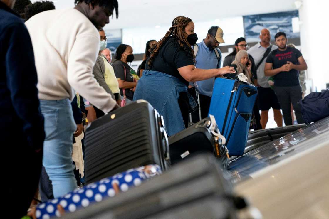 Travelers pick up their baggage while arriving at Ronald Reagan Washington National Airport in Arlington, Virginia, on July 2, 2022 Travelers pick up their baggage while arriving at Ronald Reagan Washington National Airport in Arlington, Virginia, on July 2, 2022