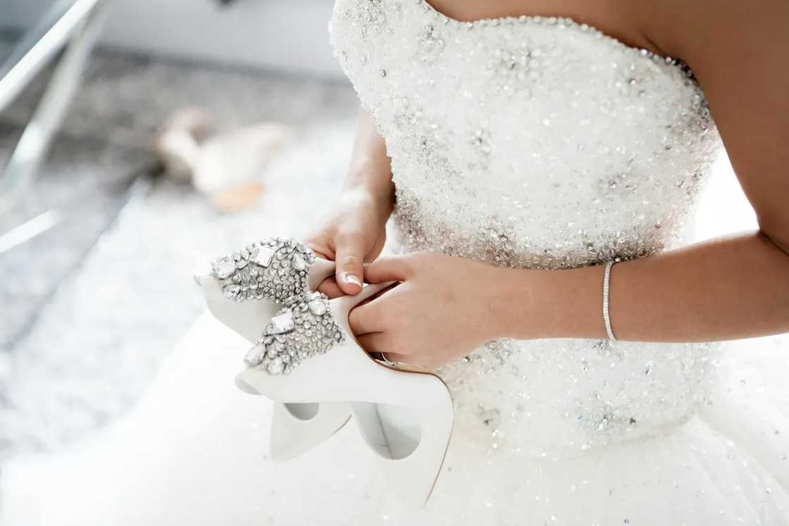 A bride holding her shoes