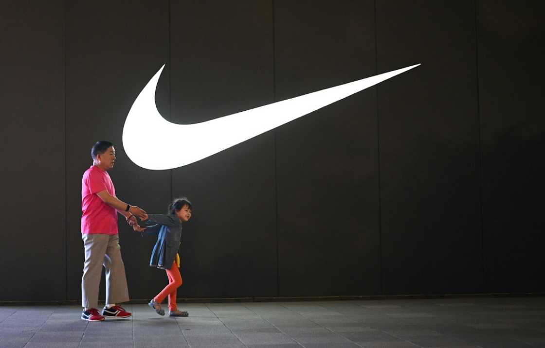 An elderly man and a child walk past a Nike logo in Wangfujing shopping district in Beijing in June 2021