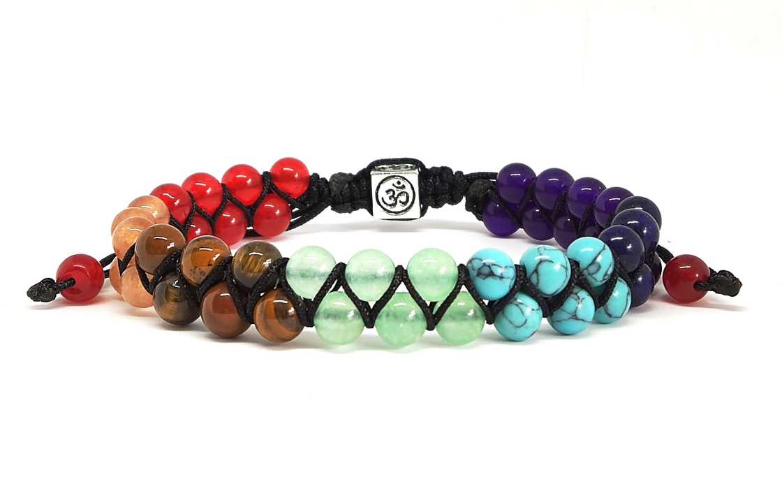 A multicoloured chakra bracelet rests against a plain background A multicoloured chakra bracelet rests against a plain background