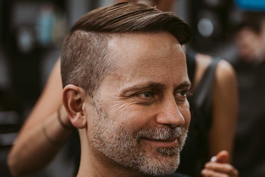 An older man is rocking a disconnected undercut with a beard